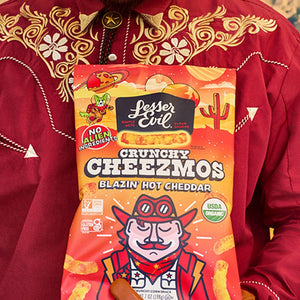 A person in a red embroidered shirt holds a Maurices Must-haves Box from LesserEvil Snacks.