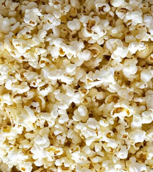 A close-up view of a pile of freshly popped popcorn, showing fluffy white pieces with a hint of yellow from butter.