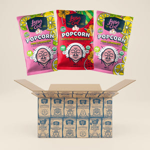 Three vibrant LesserEvil Snacks bags—two Pink Lemonade Popcorn, one Watermelon Hibiscus—float above an open Sweet Summer Box packed with more popcorn in matching designs.