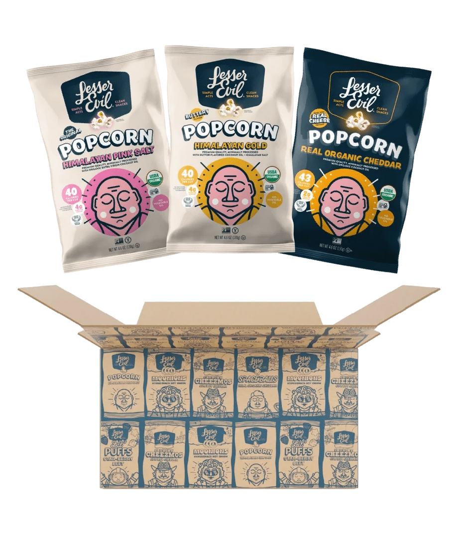 Three bags from the LesserEvil Snacks Popcorn Best Sellers Box—featuring Himalayan Pink Salt, Real Organic Cheddar, and Himalayan Gold popcorn—above an open box of neatly arranged bags.