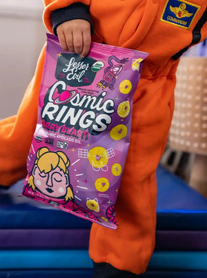 A person in an orange astronaut suit holds a Lil Favorites Kids Snacks Box by LesserEvil Snacks with colorful, playful packaging.