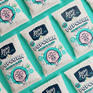 Bags of OrganicPopcorn Homers Blend Organic Popcorn are arranged in a neat diagonal pattern on a teal background, each displaying a cartoon face and product details.