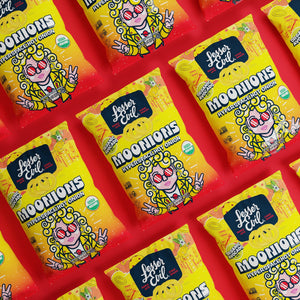 Rows of bright yellow LesserEvil Hyperspace Hot Onion Moonions snack bags with hot onion rings made with avocado oil and a cartoon onion on a vibrant red background.
