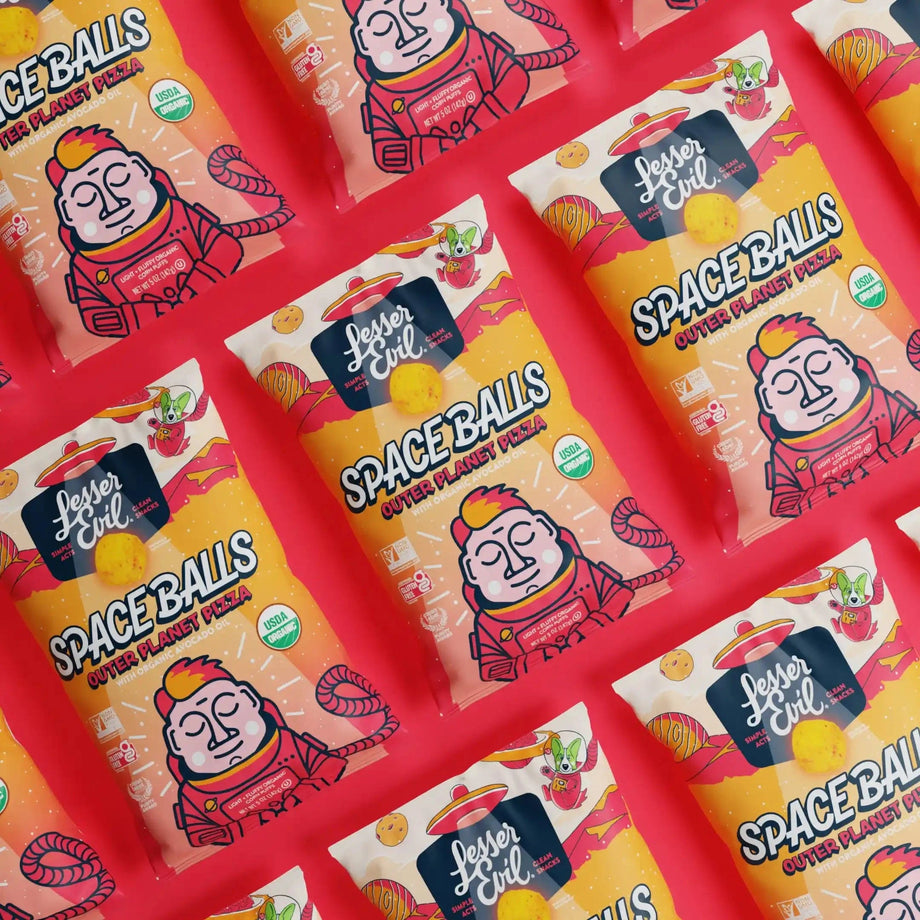 Bags of SpaceBalls Outer Planet Pizza Space Balls featuring a cartoon astronaut on orange packages are displayed in a grid on a bright pink background.