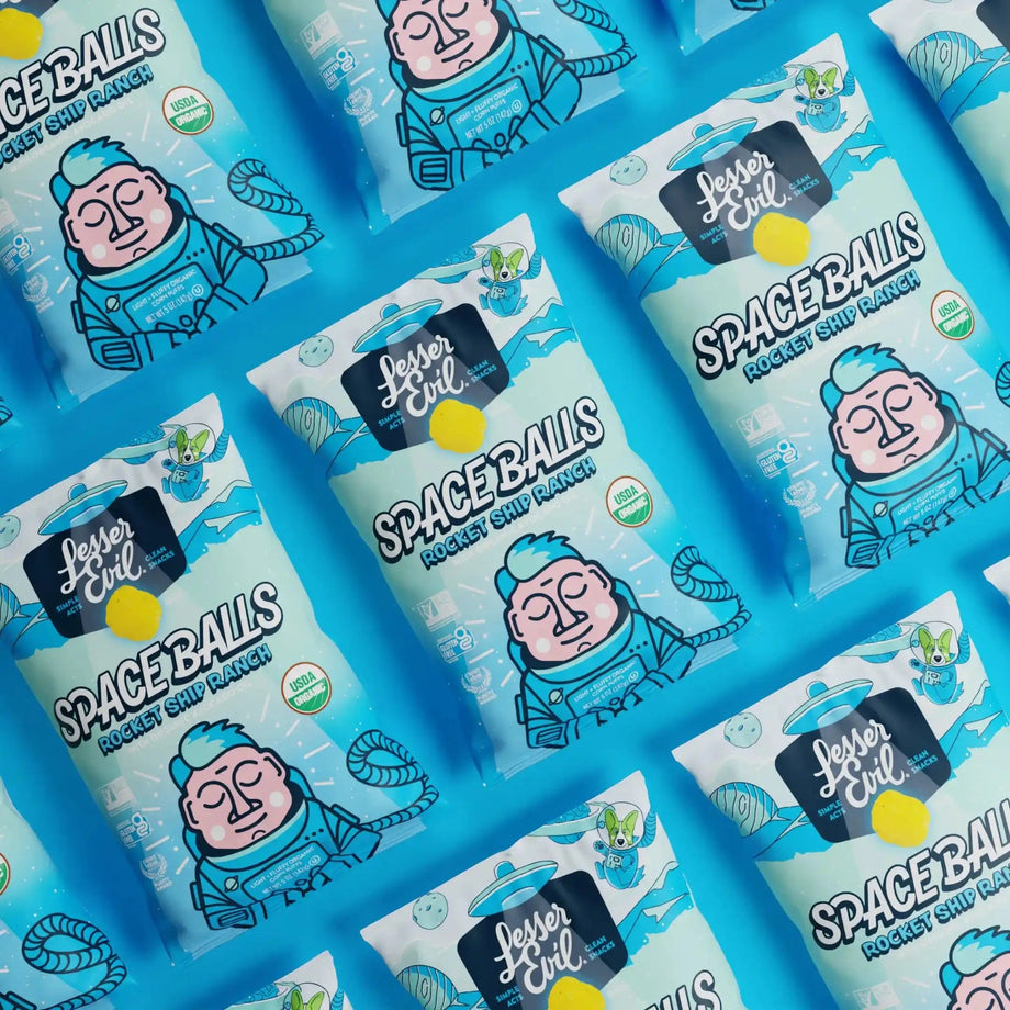Several bags of SpaceBalls Rocket Ship Ranch snacks, with cartoon astronauts, are displayed diagonally on a vibrant blue background.