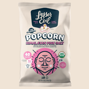 A bag of OrganicPopcorn Himalayan Pink Salt Organic Popcorn, made with extra-virgin coconut oil, features a pink meditating figure and organic certification badges on a light background.
