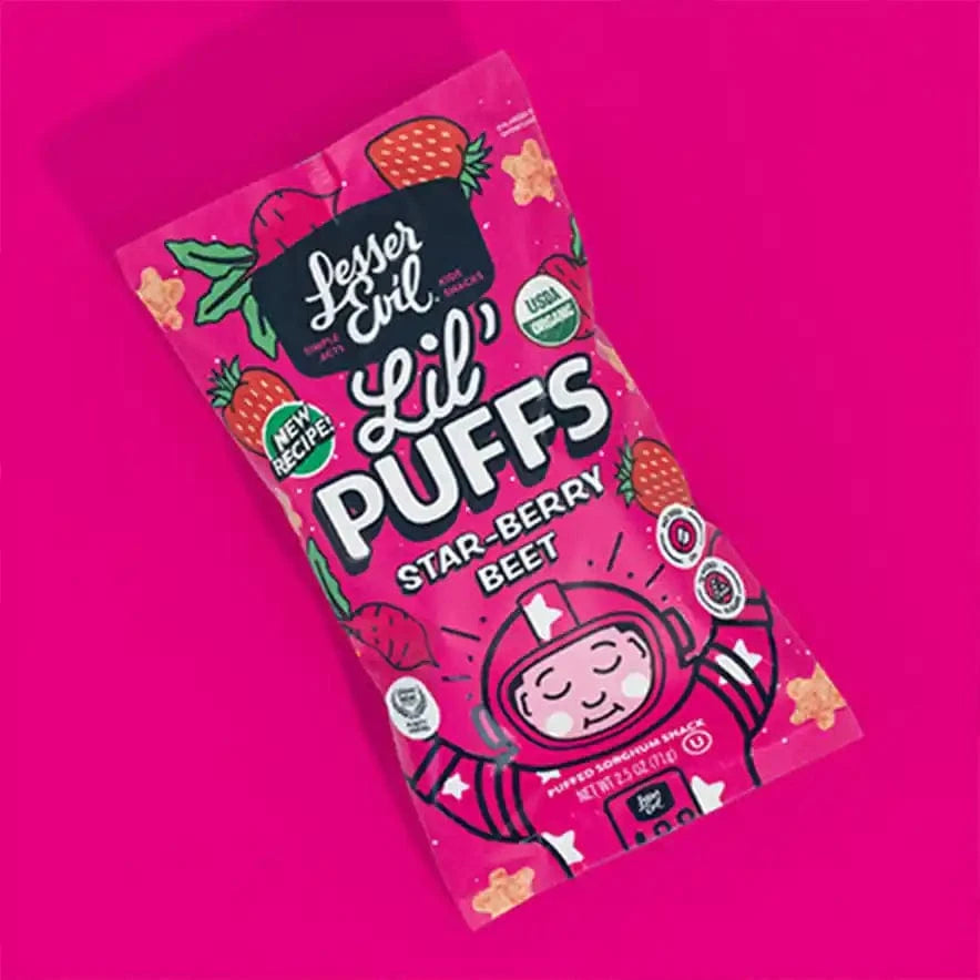 A bright pink box of Stellas Stars Lil Puffs by LesserEvil Snacks, with strawberries, cartoon stars, and a smiling helmeted character on the front.