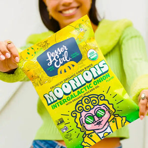 A smiling woman in a green sweater holds a box of LesserEvil Snacks Snacktime Box close to the camera.