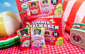 LesserEvil Snacks' Summer Popcorn Snack Pack features organic popcorn in watermelon hibiscus & pink lemonade flavors, plus a large box, inflatable watermelon, radio, and red-striped blanket.