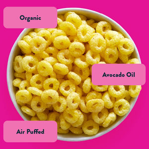 A white bowl of Berry Blast Cosmic Rings by LesserEvil—kid-friendly, air-puffed rings with organic fruit powders and avocado oil—on a bright pink background.