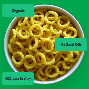 A bowl of LesserEvil Intergalactic Onion Moonions—yellow, ring-shaped snacks labeled Organic, No Seed Oils, 43% Less Sodium, and made with clean ingredients.