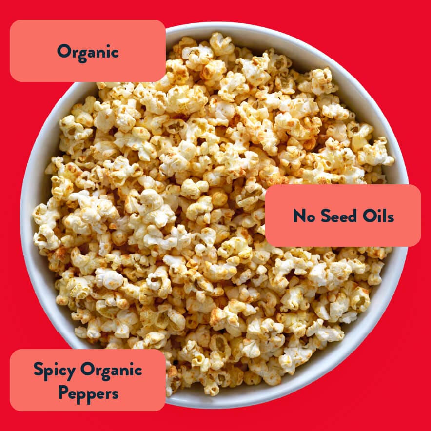 A bowl of Fiery Hot Organic Popcorn by LesserEvil on a red background, labeled Organic, No Seed Oils, and made with spicy organic habanero peppers.