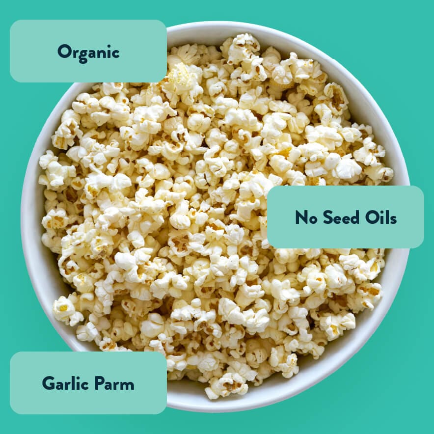 A bowl of Homers Blend Organic Popcorn by OrganicPopcorn on a teal background, labeled Garlic Parmesan, Organic, No Seed Oils, and Organic Garlic Powder.