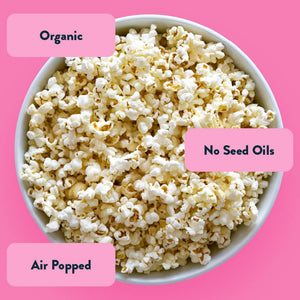 A bowl of OrganicPopcorn Himalayan Pink Salt Organic Popcorn on a pink background, featuring extra-virgin coconut oil, organic, no seed oils, air popped.