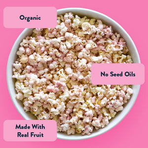 LesserEvil Pink Lemonade Popcorn with pink pieces pops against a pink backdrop. Organic, no seed oils, made with real fruit—perfect for summer!.