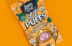 A bag of LesserEvil Broccoli Cheddar Blast Lil Puffs on an orange background, with cartoon broccoli, cheese, and a smiling astronaut on the package.