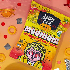 A bag of LesserEvil Hyperspace Hot Onion Moonions corn rings with avocado oil sits on a colorful background, radiating snack vibes and bright decorations.