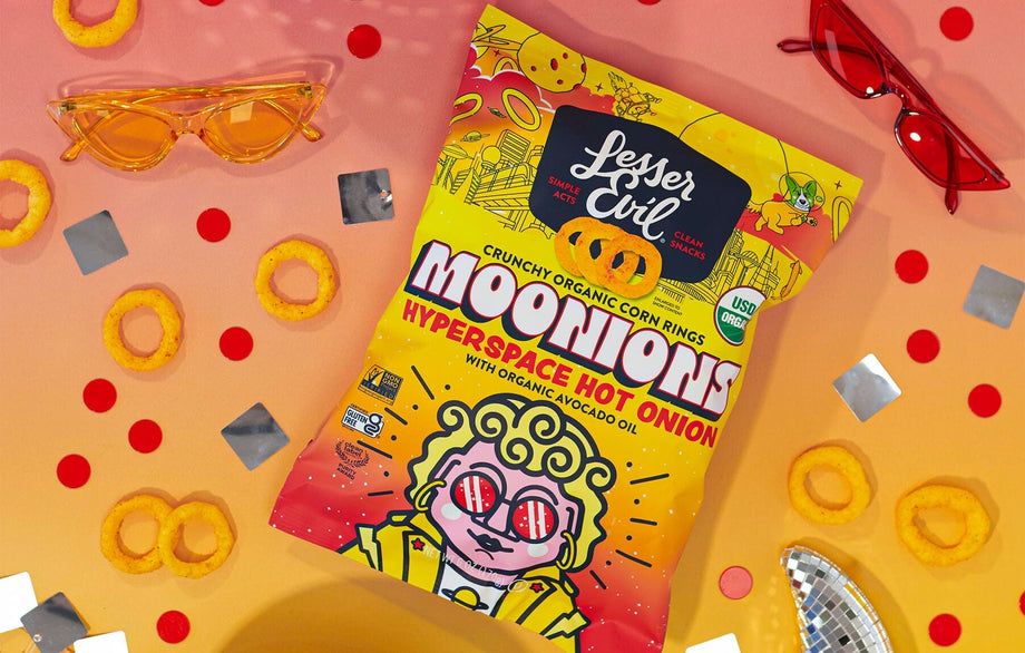 A bag of LesserEvil Hyperspace Hot Onion Moonions corn rings with avocado oil sits on a colorful background, radiating snack vibes and bright decorations.