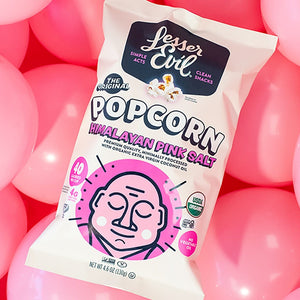 A bag of OrganicPopcorn’s Himalayan Pink Salt Organic Popcorn is surrounded by pink balloons, creating a playful and colorful backdrop.