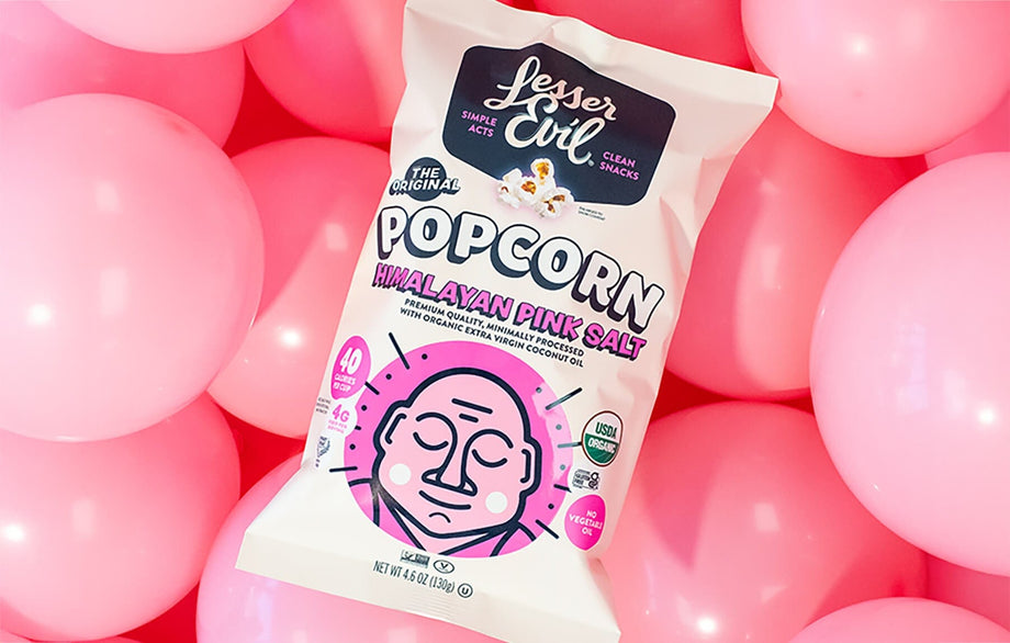 A bag of OrganicPopcorn’s Himalayan Pink Salt Organic Popcorn is surrounded by pink balloons, creating a playful and colorful backdrop.