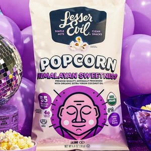 A bag of OrganicPopcorn Himalayan Sweetness Gourmet Popcorn is surrounded by purple balloons, a disco ball, and a purple lava lamp.